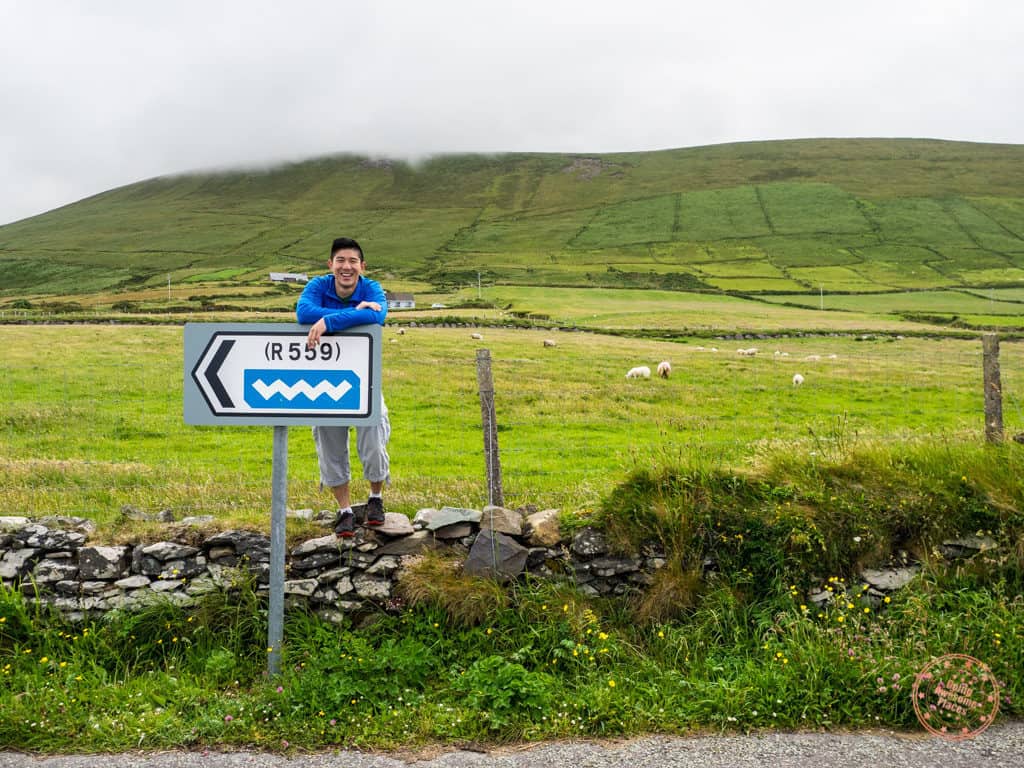 standing in front of the wild atlantic way sign near dingle ireland