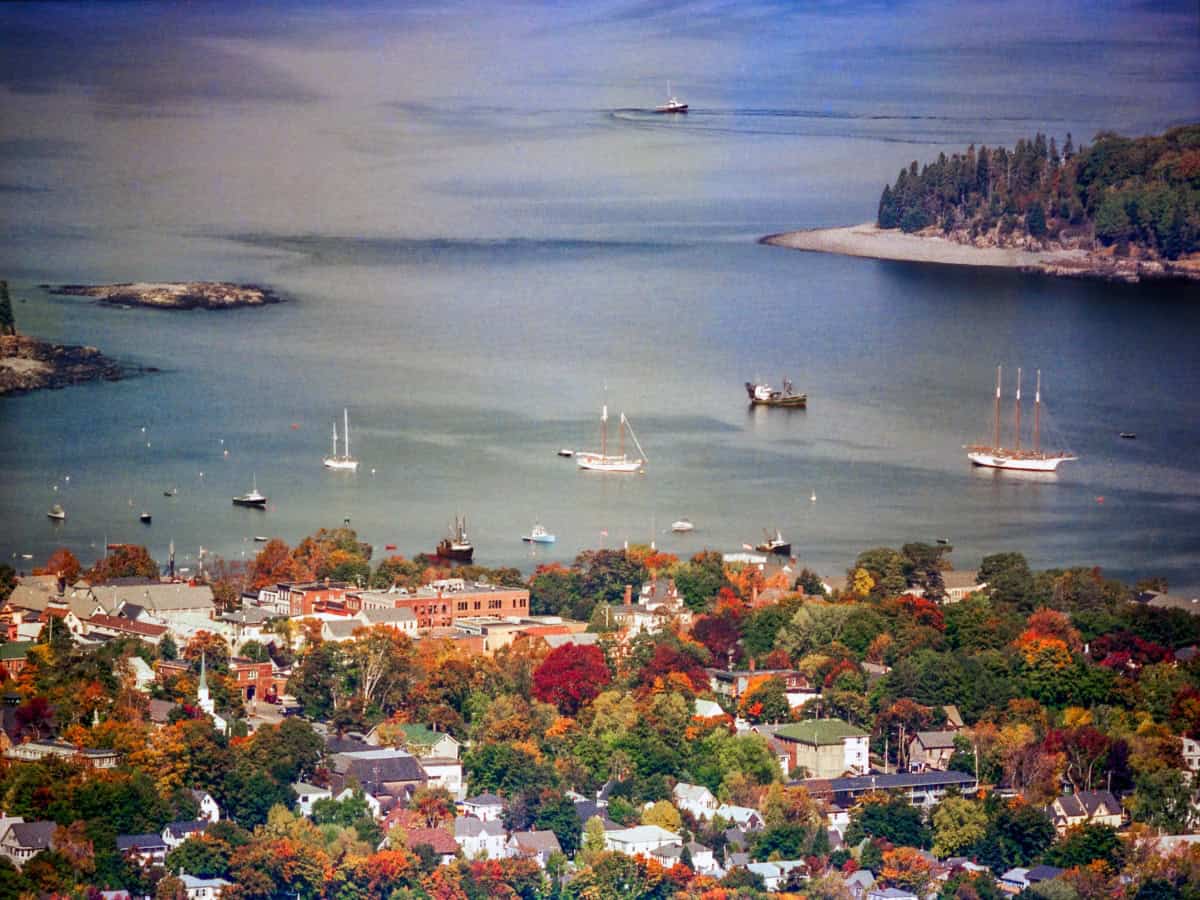 aerial view over bar harbor maine in the fall with sailboats on water and fall colored trees scattered through town