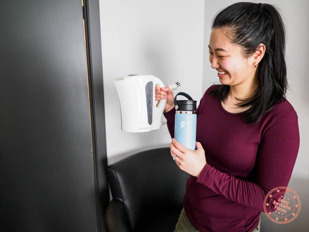 woman holding hot water kettle and water bottle at chateau madelinot in the magdalen islands