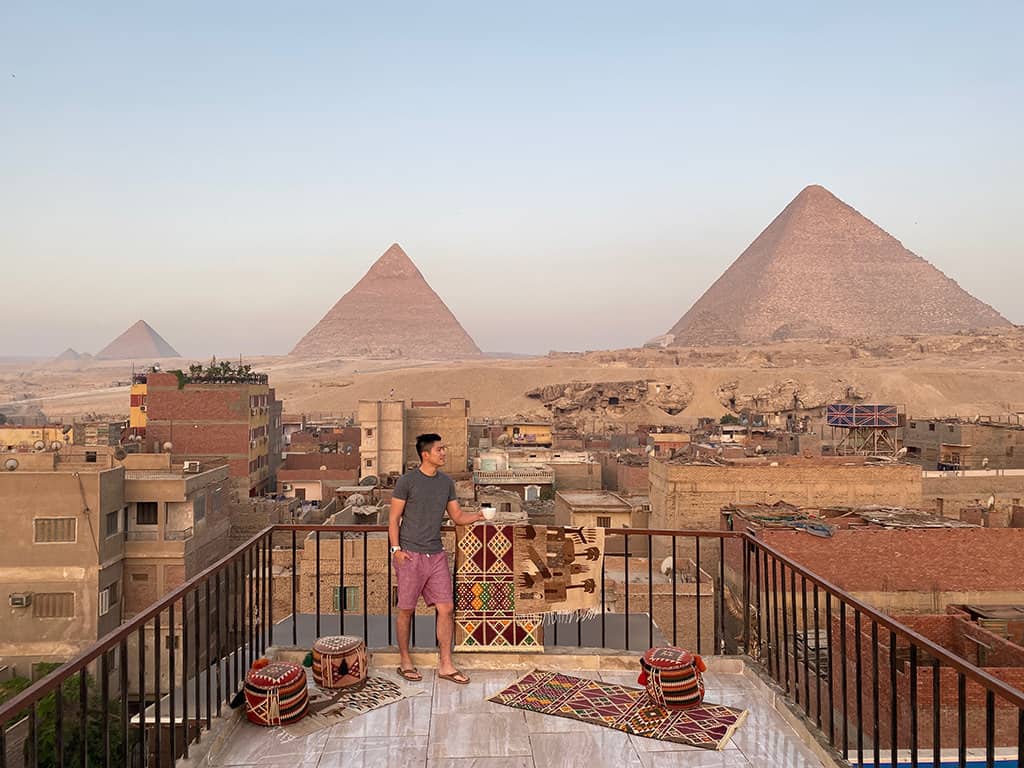 man standing on rooftop with pyramids of giza in the background