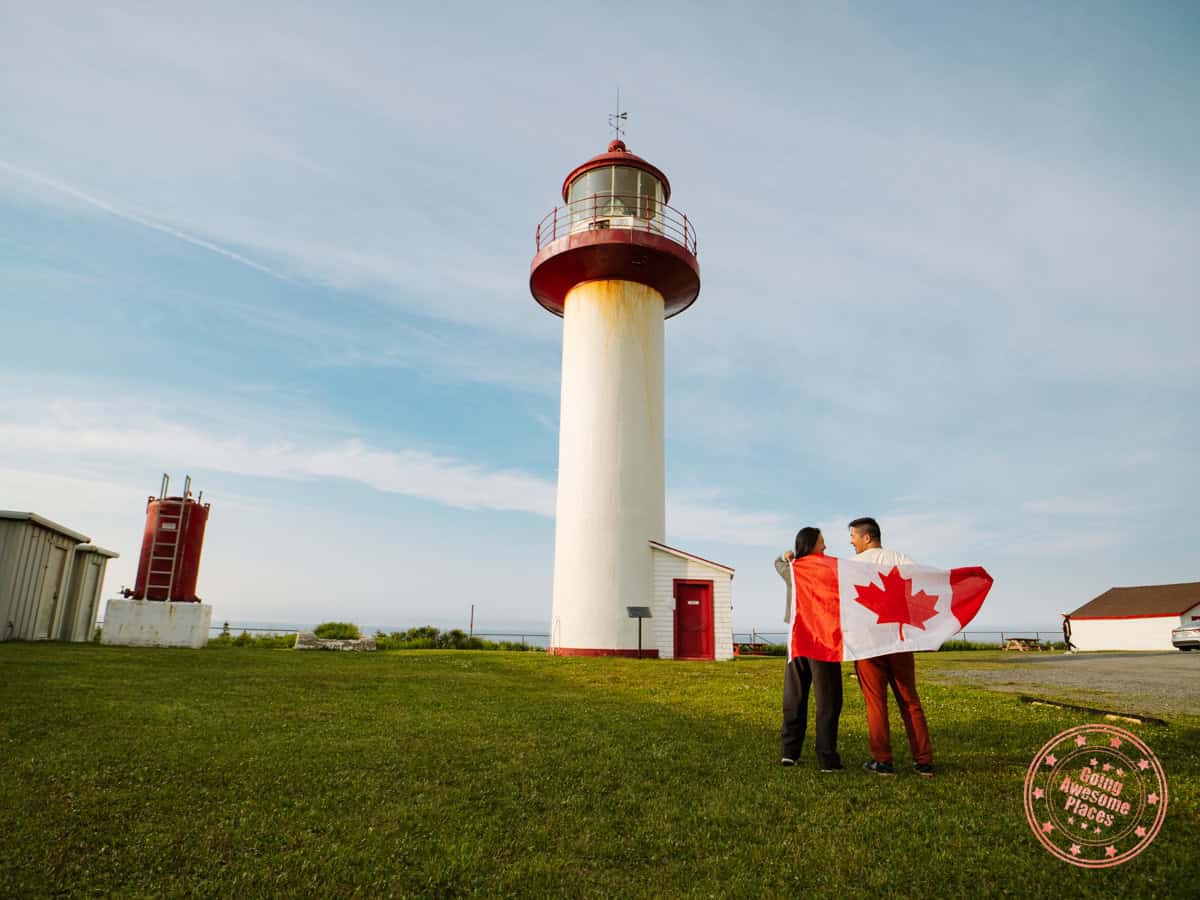 asian couple with canada flag in front of cap de la madeleine lighthouse