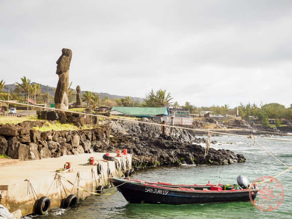 hanga roa harbor with boats and moai on platform in town