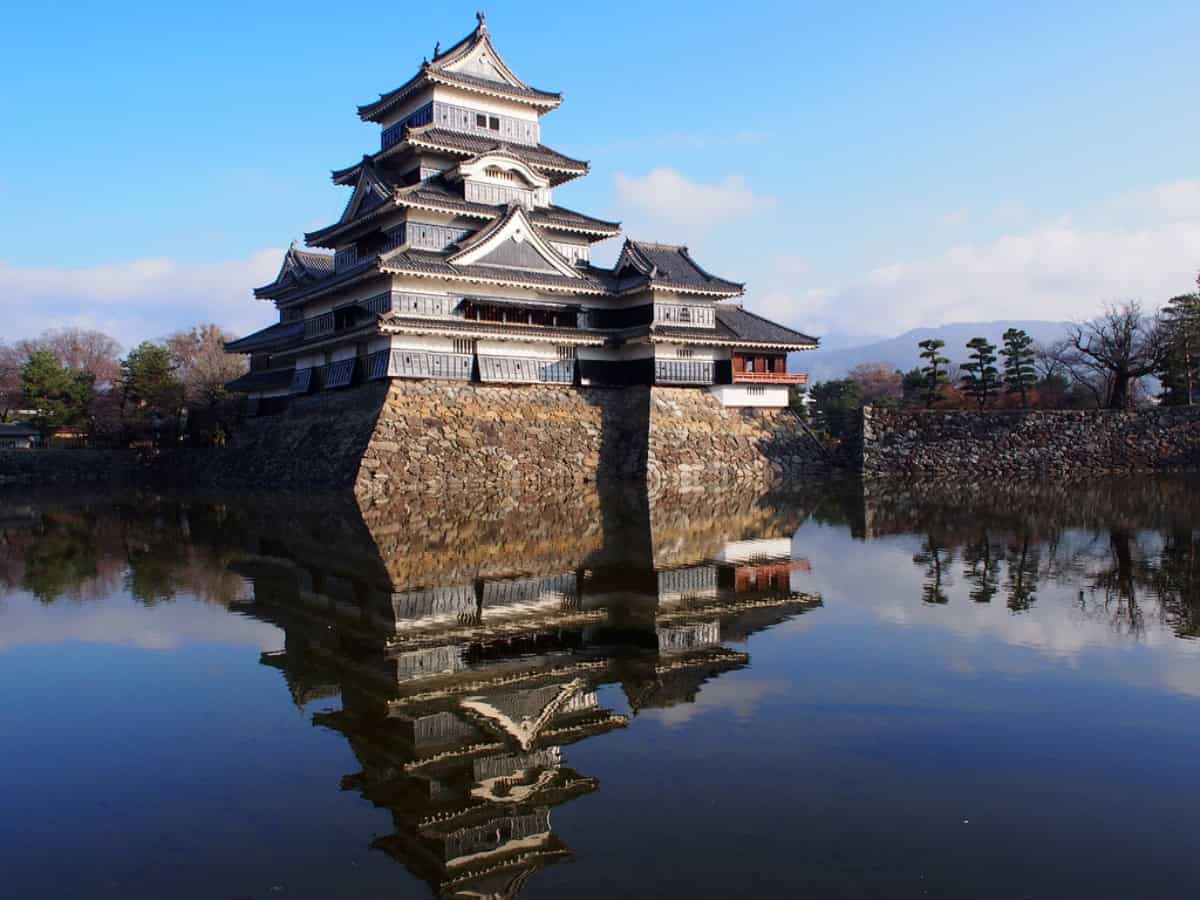 view of matsumoto castle reflecting in the water below