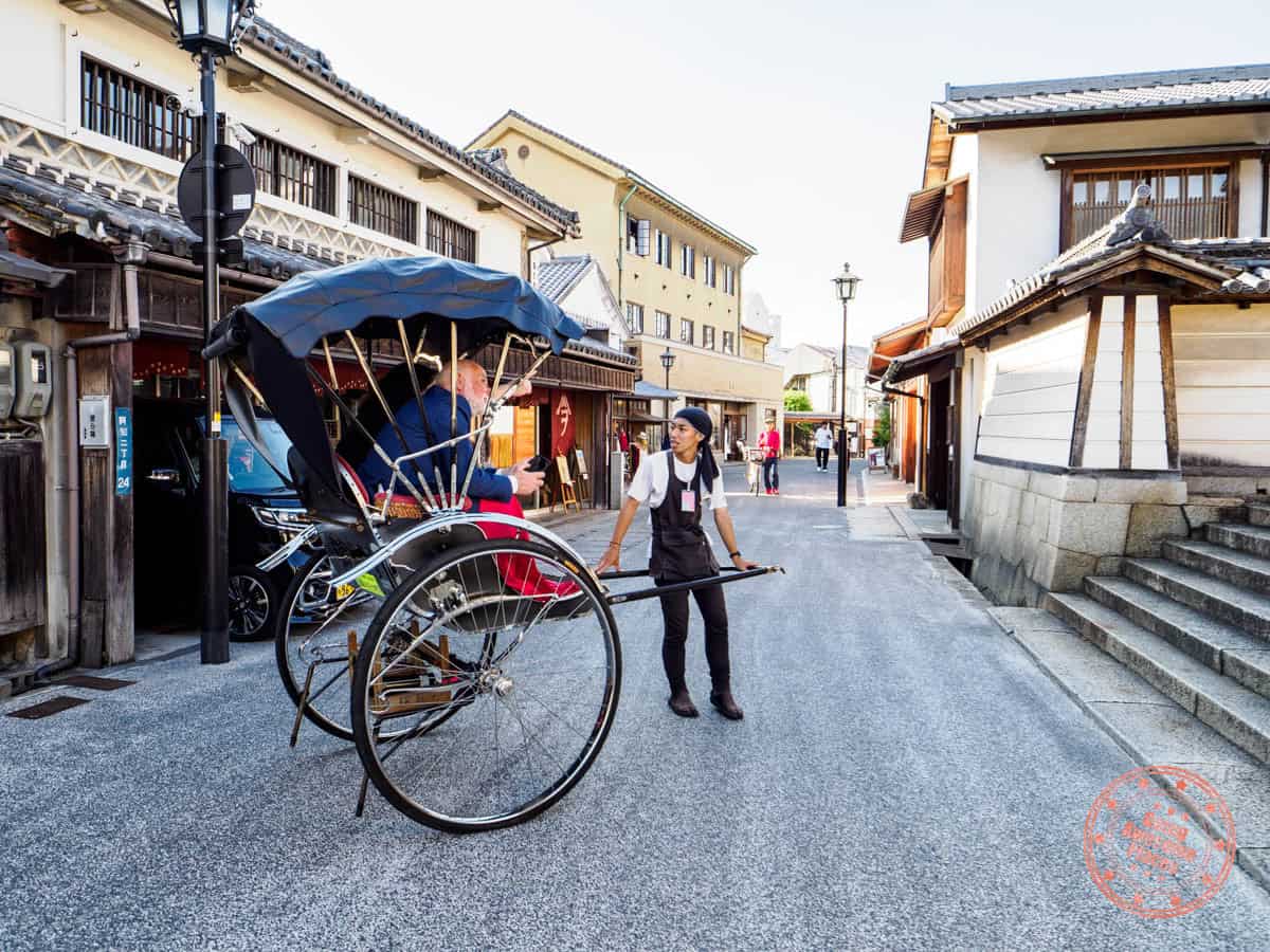 tourist riding on a man-pulled carriage through kurashiki bikan historical quarter