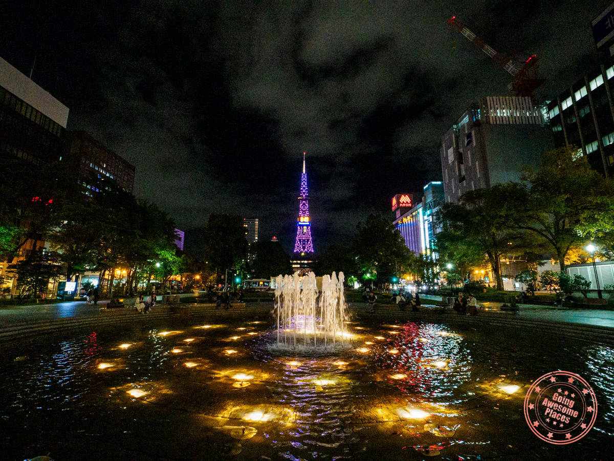 sapporo tower lit up at night beyond fountain