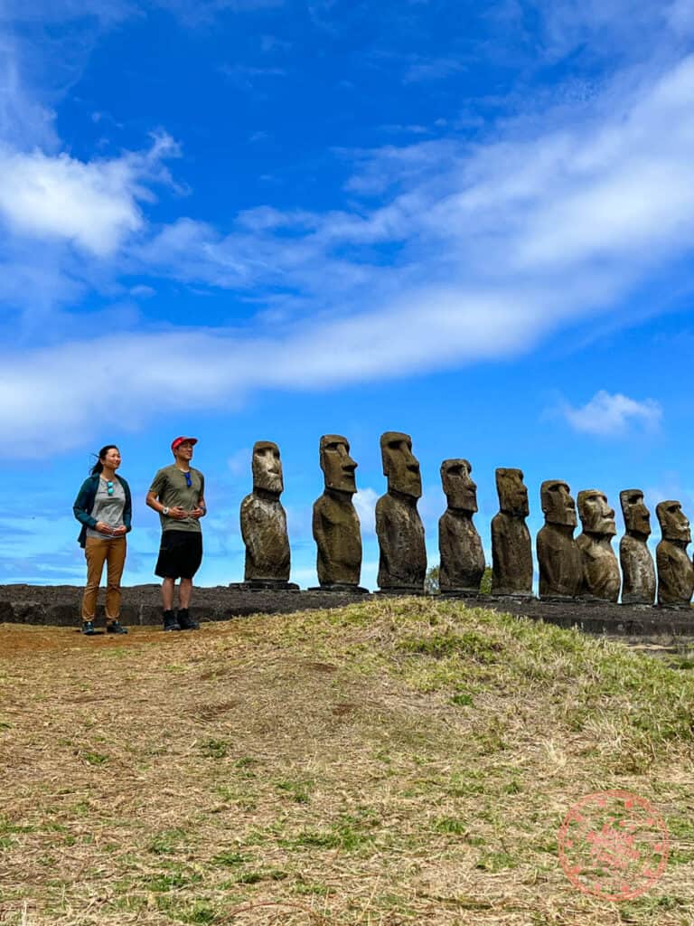 couple standing in line with the moai at tongariki on easter island