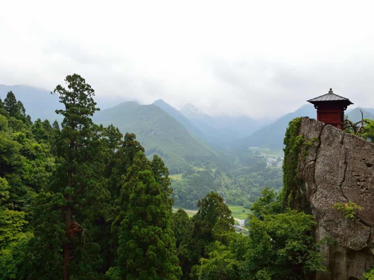 distant view of a temple sitting amongst mountains in yamagata