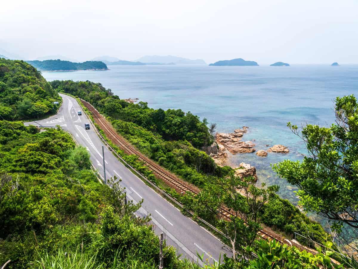 aerial view over long road along stretch of coast in yamaguchi